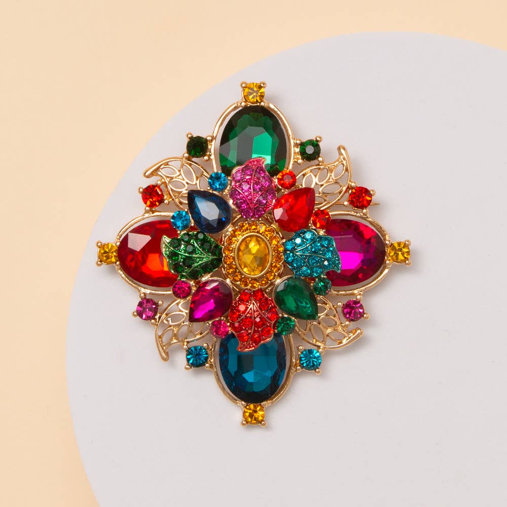 Multicolored gemstone brooch on a white stand.