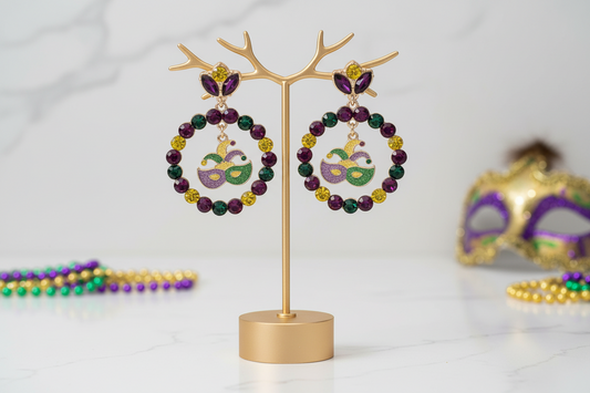 These Mardi Gras mask circle drop statement earrings showcase a festive beaded ring design with a playful mask charm centerpiece. Designed to stand out, they are perfect for Mardi Gras celebrations, themed parties and parades. 